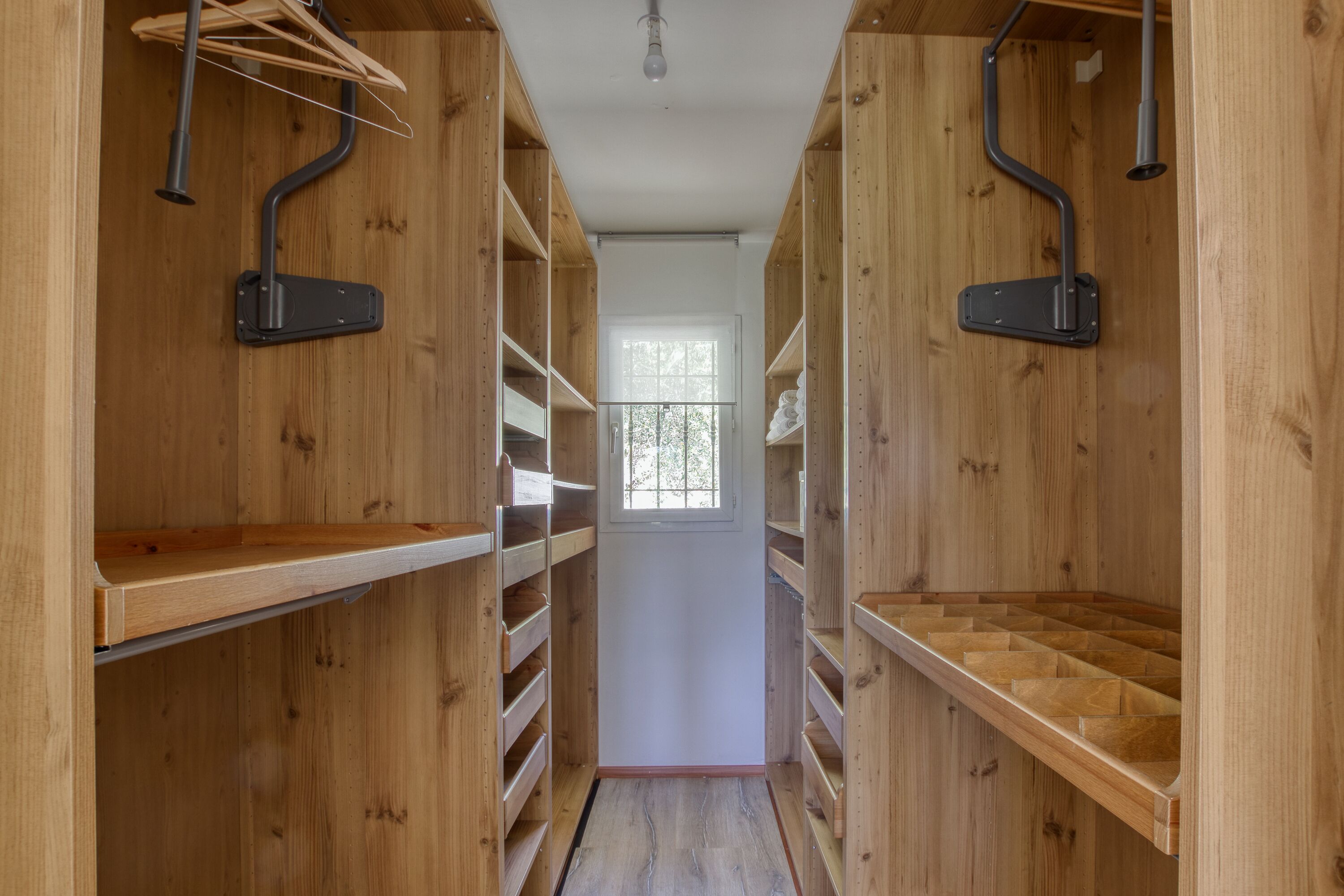 Un estrecho pasillo de madera con estanterías empotradas y percheros.