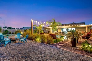 A modern house with a pool, outdoor seating, and string lights.