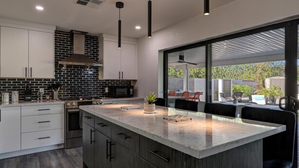 A modern kitchen with a large island, dark wood cabinets, and a view of the outdoor patio. - Gorgeous Scottsdale Home w/ Heated Pool (Scottsdale)
