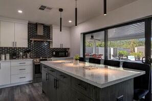 A modern kitchen with a large island, dark wood cabinets, and a view of the outdoor patio.