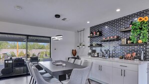 A modern kitchen with white cabinets, a black backsplash, and a dining area with a large table and chairs. - Gorgeous Scottsdale Home w/ Heated Pool (Scottsdale)