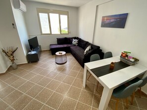Un salon comprenant un canapé, une table basse, un téléviseur et un coin repas avec une table et des chaises.