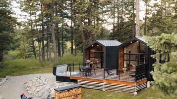 A cabin with a deck, outdoor seating, and a fire pit.