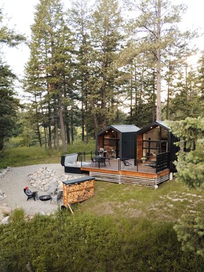 A cabin with a deck, outdoor seating, and a fire pit.