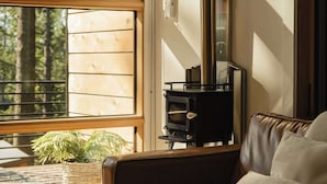 Ein modernes Wohnzimmer mit einer Ledersofa, einem Kamin und einem großen Fenster mit Blick auf Bäume.