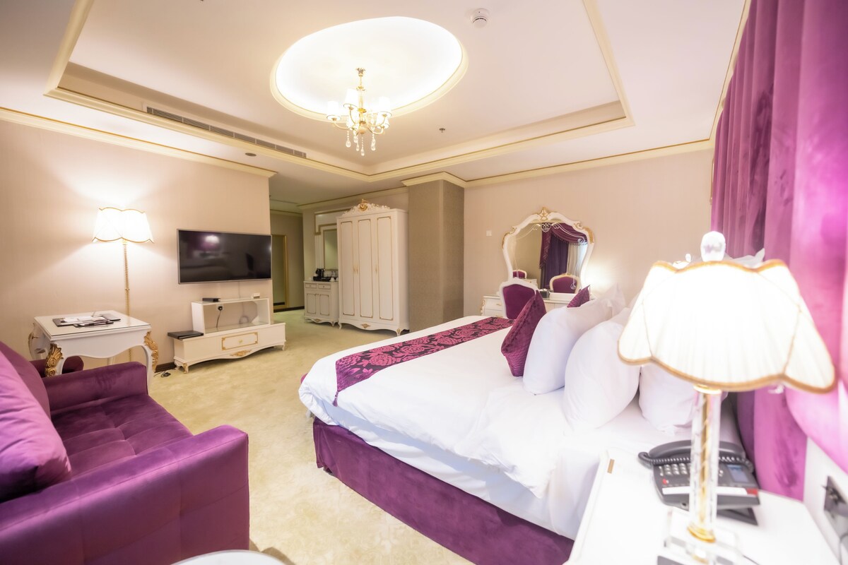 Une chambre d’hôtel avec un grand lit, une télévision, une armoire, un bureau et une chaise.