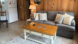 A cozy living room with a sofa, coffee table, and a refrigerator. - Charming 1-bedroom cottage in Ferry Beach Saco, ME, perfect for a cozy getaway for two. (Saco)