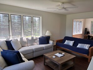 A living room with a sofa, a coffee table, and a ceiling fan.