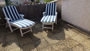 To komfortable loungestole på en tagterrasse med udsigt til fjerne bjerge og bybelysning.