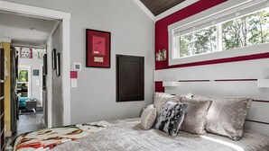 Un dormitorio con cama, ventana y puerta que da a otra habitación.