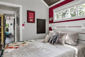 A bedroom with a bed, a window, and a door leading to another room. - The Dolly House at The Retreat at Water's Edge (Tracy City)