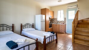Een kamer met twee bedden, een keuken en een trap.