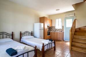 Une pièce avec deux lits, une cuisine et un escalier.
