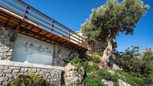 A stone building with a wooden balcony and a sign that reads 'Afrosti.' - Apartment 'Yakinthos' with Sea View, Wi-Fi and Air Conditioning (LEFKADA)