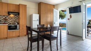 A kitchen with wooden cabinets, a built-in oven, a refrigerator, and a dining table with chairs. - Apartment 'Yakinthos' with Sea View, Wi-Fi and Air Conditioning (LEFKADA)