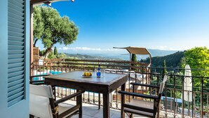 A terrace with a table, chairs, a pool, and a view of the landscape. - Apartment 'Yakinthos' with Sea View, Wi-Fi and Air Conditioning (LEFKADA)