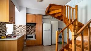 Una cucina con mobili in legno, un forno a microonde, un frigorifero e una scala in legno.