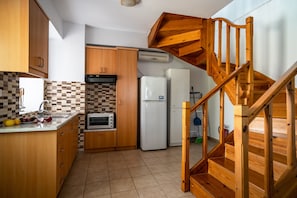 Une cuisine avec des meubles en bois, un four à micro-ondes, un réfrigérateur et un escalier en bois.