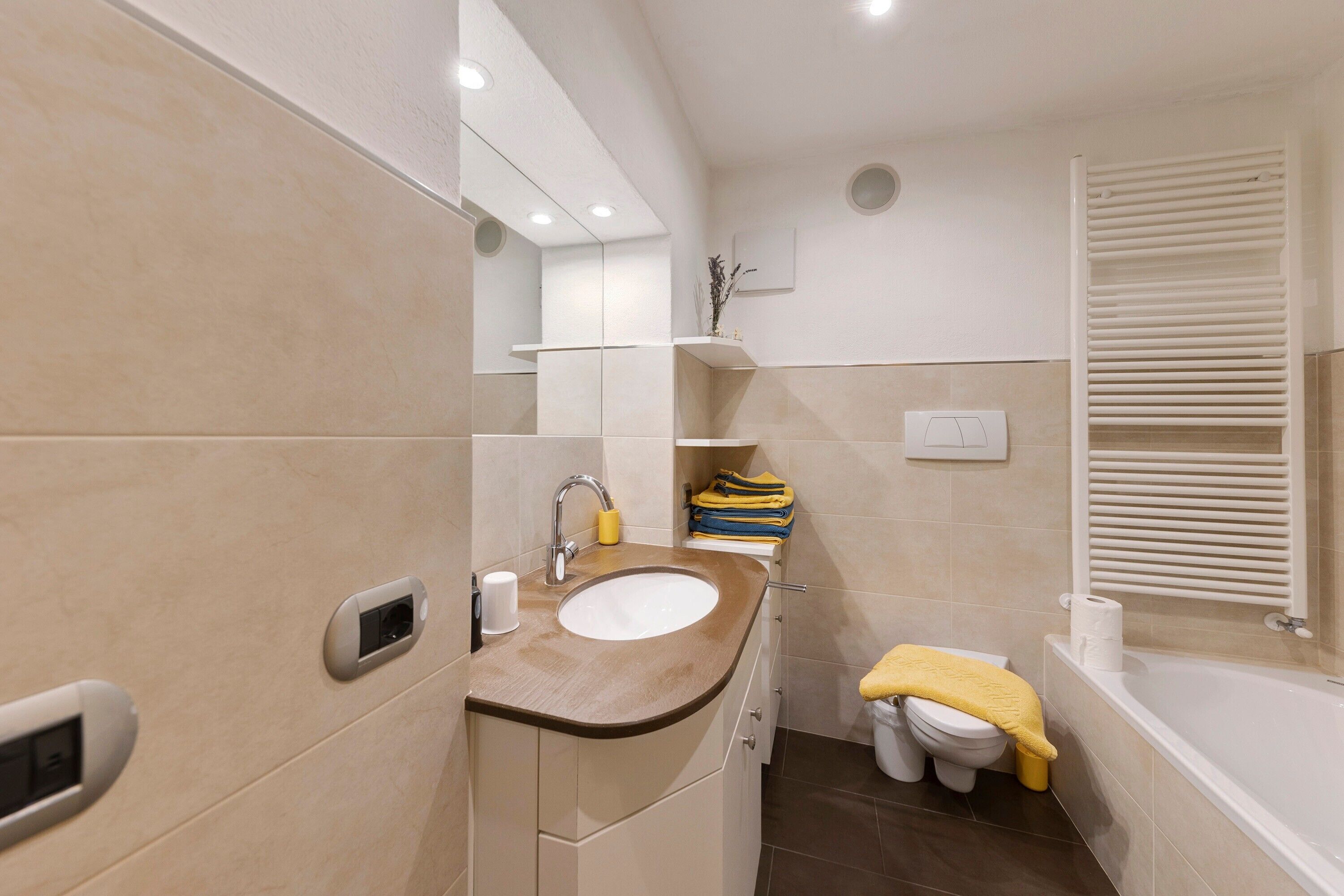 Un baño con lavamanos, espejo, inodoro y bañera.