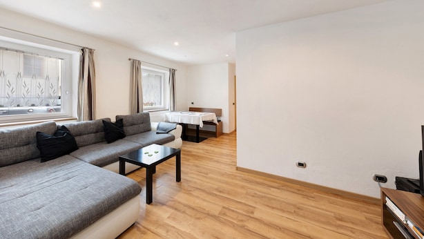 Een moderne woonkamer met een bank, een bijzettafeltje en een eethoek met een tafel en stoelen.