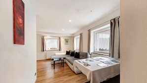 Een moderne woonkamer met een bank, een tafel met tijdschriften en een groot raam met gordijnen.