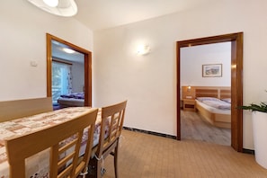 Une pièce comprenant une table à manger, des chaises, un lit, une table de chevet, une lampe et un tableau au mur.