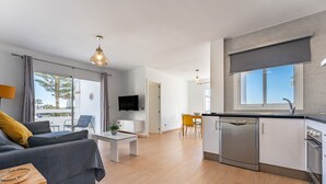 Un salon moderne comprenant un canapé, une table à manger et un coin cuisine équipé d’un lave-vaisselle et d’une fenêtre.