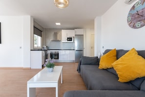 Una sala de estar moderna con un sofá, una mesa de centro y una cocina al fondo.