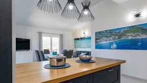 A modern kitchen with a wooden countertop, black cabinets, and a large painting of a coastal scene. - Appartamento Vista Golfo with Sea View, Terrace & Wi-Fi (Cala Gonone)