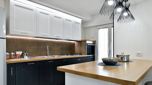 A modern kitchen with dark cabinets, a wooden countertop, and a built-in oven. - Appartamento Vista Golfo with Sea View, Terrace & Wi-Fi (Cala Gonone)