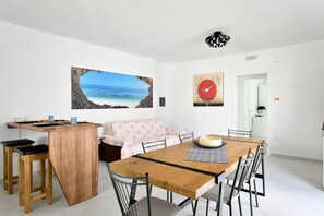 Un espace repas comprenant une table en bois, des chaises, un canapé et un comptoir de cuisine.