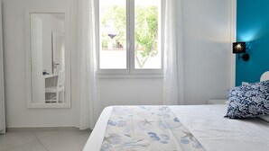 A bedroom with a bed, a window with curtains, a chair, and a wall-mounted lamp. - Appartamento Prato al Mare with Garden, A/C & Wi-Fi (Cala Gonone)