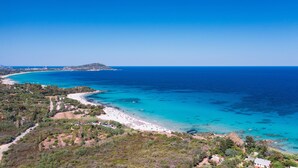Un paisaje costero con playa, mar azul cristalino y terreno montañoso.