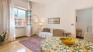 Una habitación con una cama, una silla, una mesa, una lámpara y una ventana con cortinas.