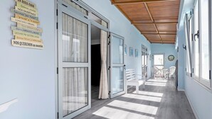 A hotel corridor with sliding glass doors, a wooden ceiling, and a dining area with chairs and a table. - Holiday Home Casa Carmencita with Sea Views, Pool and Wi-Fi (La Garita)