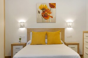 Ein Schlafzimmer mit einem Bett, zwei Nachttischen, einer Wandlampe und einem Gemälde.