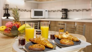 Bandeja de desayuno con cruasanes, jugo y un bol de fruta.