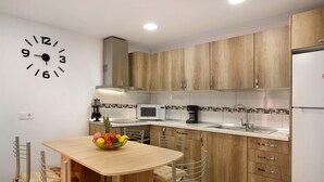 Una cocina moderna con armarios de madera, microondas, pileta y un reloj en la pared.