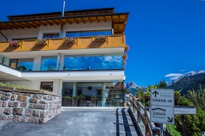 Un immeuble à plusieurs étages doté d’un balcon, d’un panneau d’inscription pour l’enregistrement et offrant une vue sur les montagnes.