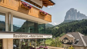 Un hotel con balcón, ventanas amplias y vistas a la montaña.