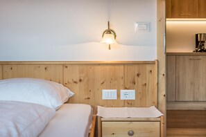 A wooden headboard with a wall-mounted light fixture, a bedside table with a drawer, and a power outlet.