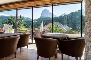 A modern interior with large windows, brown leather chairs, and a view of a mountainous landscape.