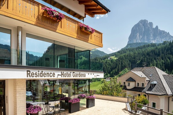 A hotel with a balcony, large windows, and a mountain view.