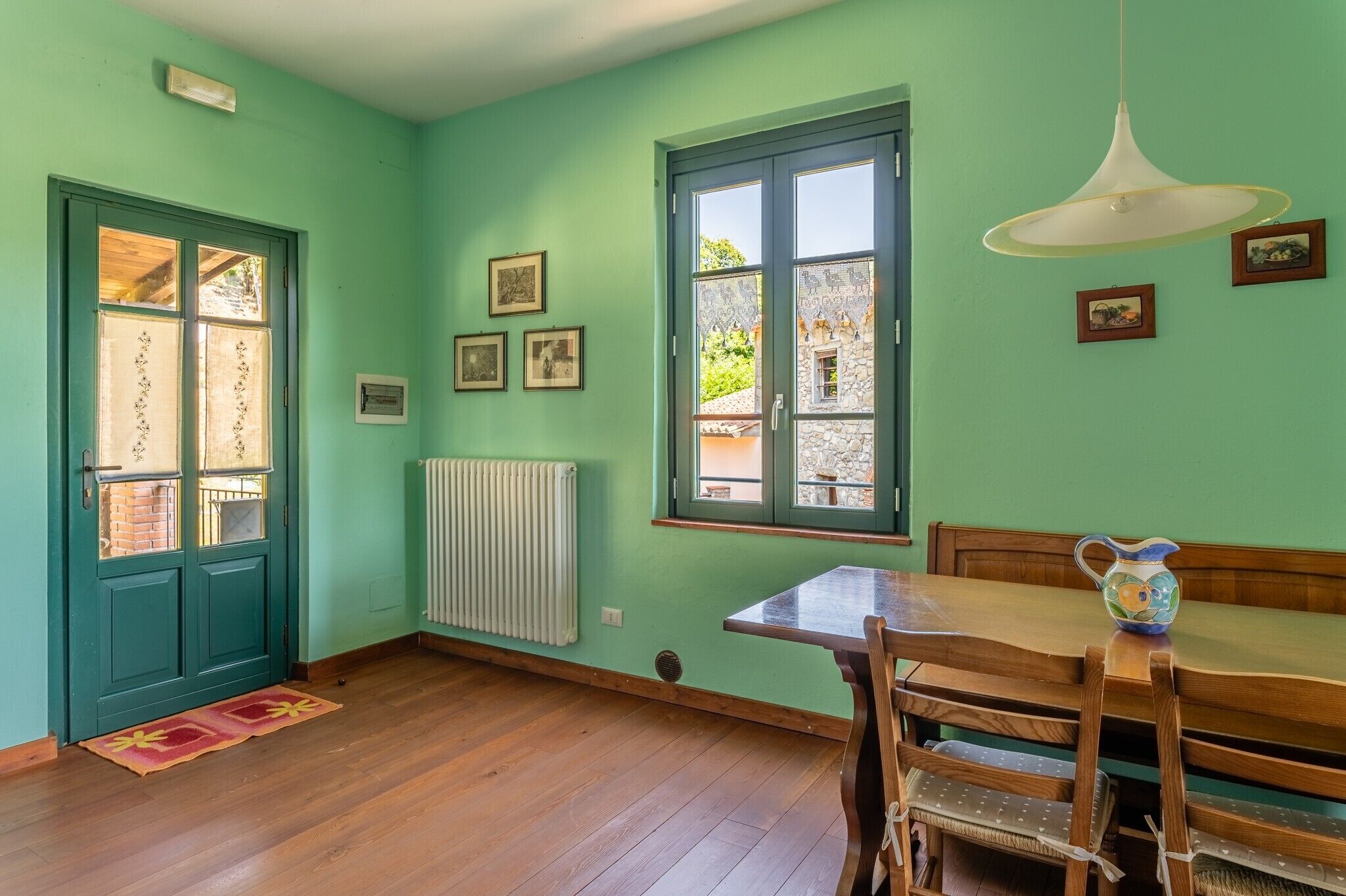 Une pièce comprenant une table à manger en bois, un banc, un radiateur et une fenêtre donnant sur un paysage agréable.