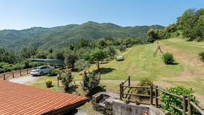 A scenic view of a mountainous area with a car parked on a gravel path, a wooden fence, and a building with a red roof. - Apartment 'Alba al Rifugio Arcobaleno' with Mountain View, Shared Pool & Wi-Fi (Popiglio)