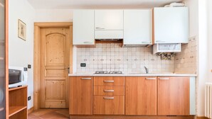 Une cuisine avec des meubles en bois, un four à micro-ondes et un dosseret carrelé.
