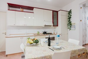 A kitchen with white cabinets, a stove, and a dining table with a patterned tablecloth.