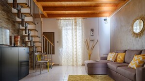 A living room with a staircase, a sofa, a rug, and a wall-mounted light fixture.