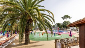 Ein Poolbereich mit Palmen, Liegestühlen und einem Wasserspielplatz.
