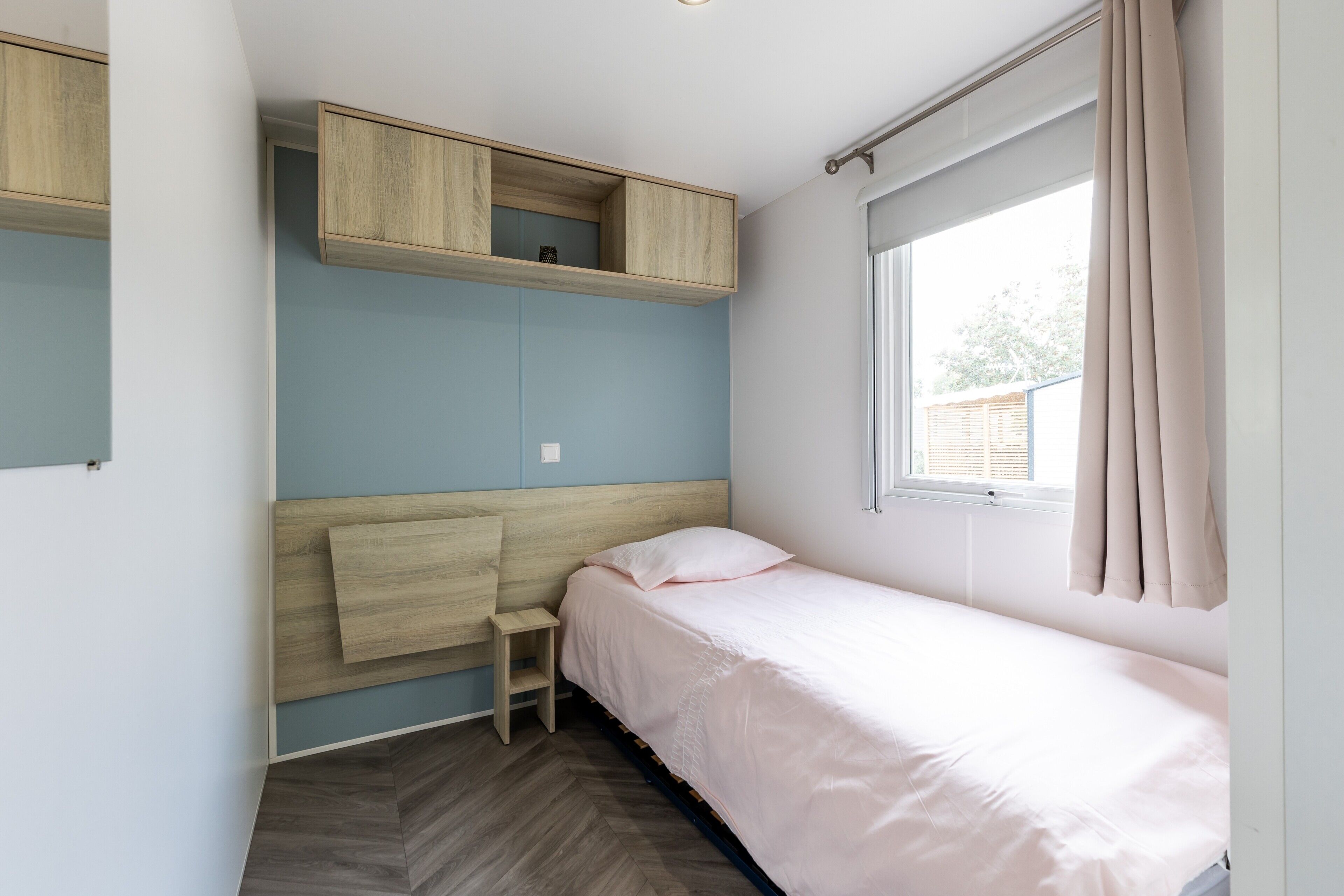 A bedroom with a bed, a desk, and a window.